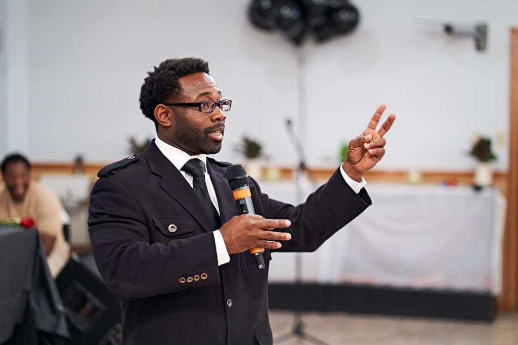 Alonzo Waheed speaking on stage with a microphone
